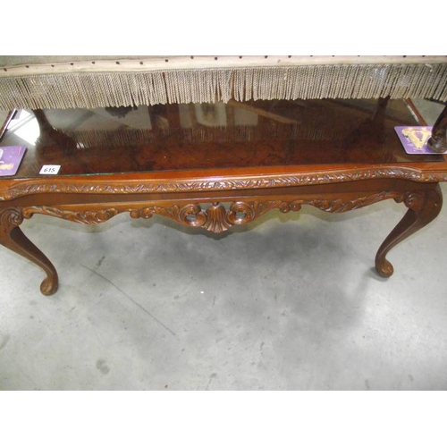 615 - A dark wood stained carved long coffee table with glass top.