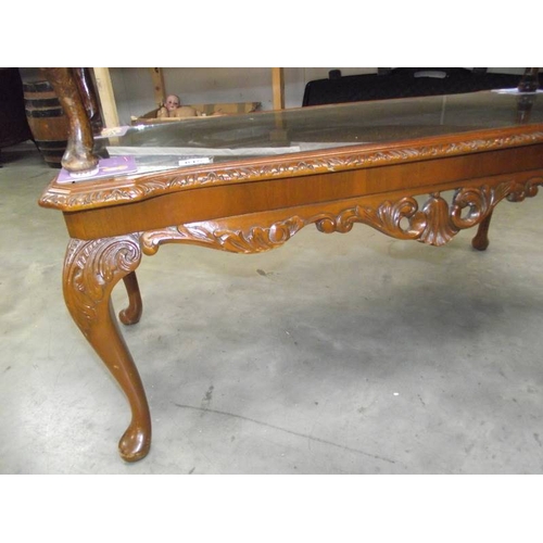 615 - A dark wood stained carved long coffee table with glass top.