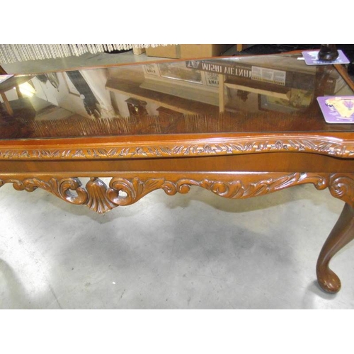 615 - A dark wood stained carved long coffee table with glass top.