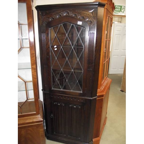 631 - A dark oak linen fold lead glazed corner cabinet.