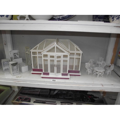 454 - A dolls house consrevatory with fancy painted white metal garden furniture