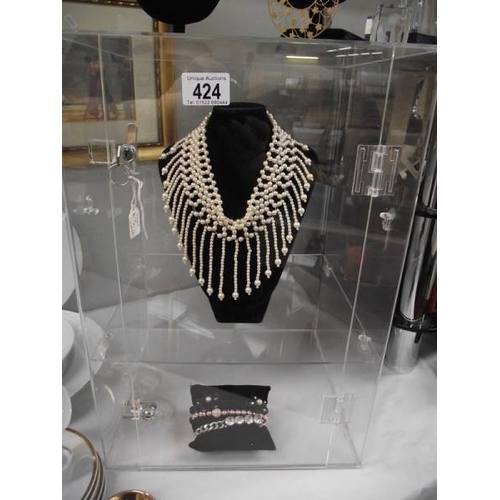 424 - A display cabinet (plastic) and a quantity of costume jewellery on stands