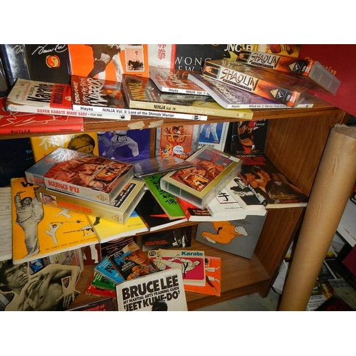 14 - Nine shelves of Bruce Lee related items, Kung Fu books. posters, videos etc.,