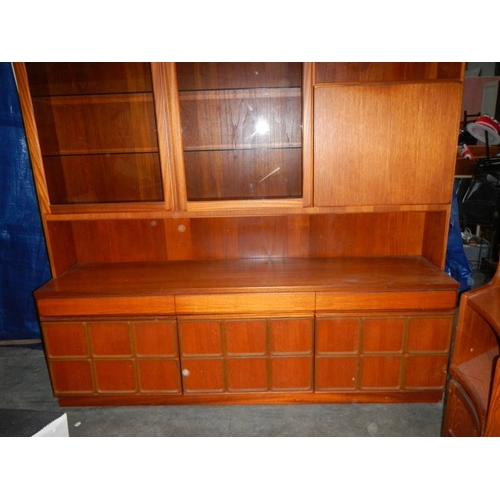 545 - A large teak wall unit with 3 doors to base, 3 drawers and glass fronted cupboards, lit.  180 x 115 ... 