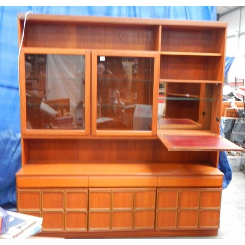 545 - A large teak wall unit with 3 doors to base, 3 drawers and glass fronted cupboards, lit.  180 x 115 ... 