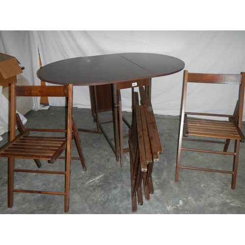 581 - A good fold out oak veneer table with 4 folding chairs inside, 135 x 97 x 74 when open.