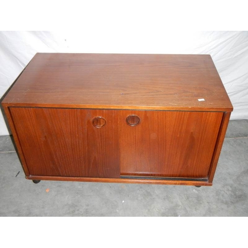 596 - A sliding door cabinet on wheels, a 1930's bedside cabinet and a G plan table.