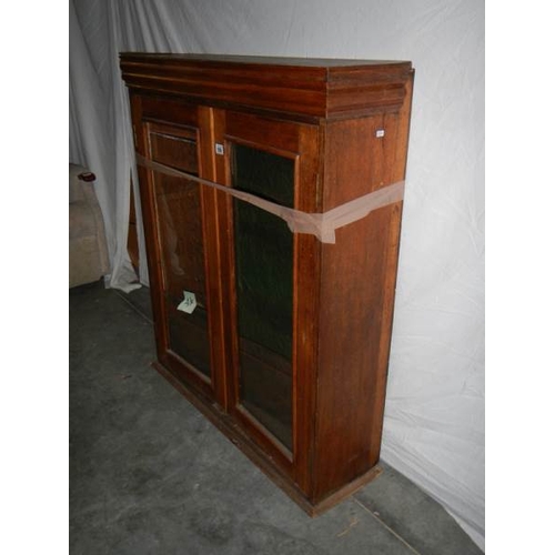 599 - A glass fronted 2 door cabinet with shelves (glass needs replacing) 115 x 98 x 30 cm.