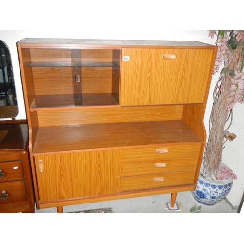 661 - A teak glazed sliding door cabinet with drop down side and three drawers.