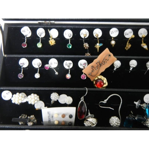 526 - A cabinet of pairs and single earrings.