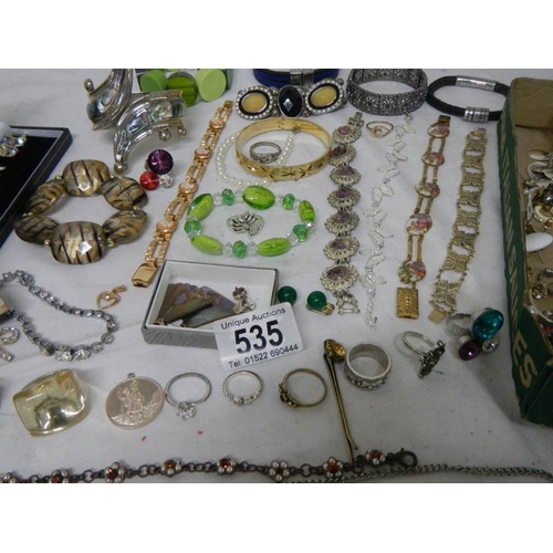 535 - A mixed lot of costume jewellery including necklaces, bangles, rings etc and a small clock.