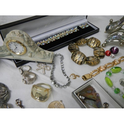 535 - A mixed lot of costume jewellery including necklaces, bangles, rings etc and a small clock.