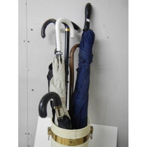 608 - A metal stick stand with 4 umbrella's and 2 walking sticks.