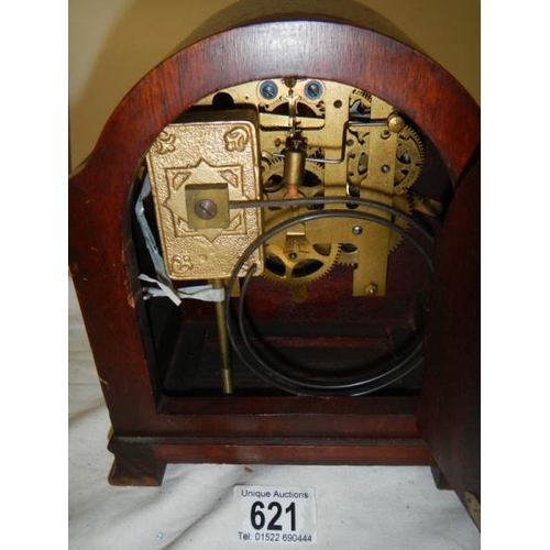 621 - An 8 day mahogany inlaid mantel clock with key and pendulum.