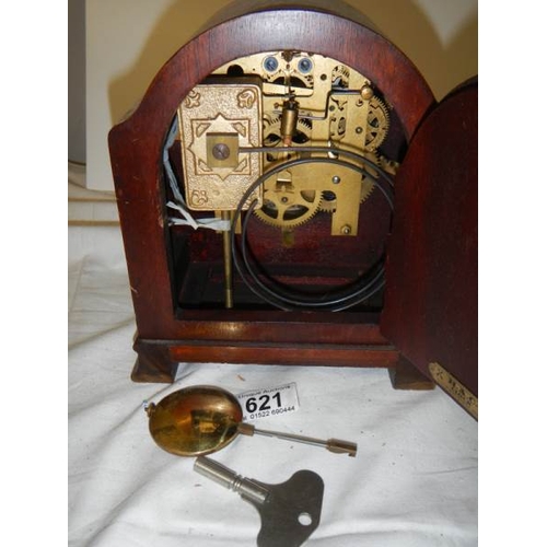 621 - An 8 day mahogany inlaid mantel clock with key and pendulum.