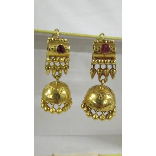 124 - A pair of (test as 24ct gold) pendant earrings set rubies.  10.4 grams.