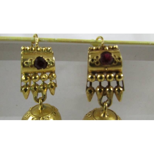 124 - A pair of (test as 24ct gold) pendant earrings set rubies.  10.4 grams.