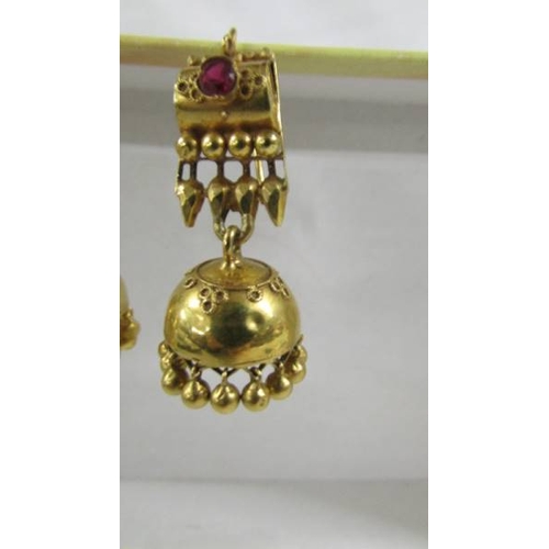 124 - A pair of (test as 24ct gold) pendant earrings set rubies.  10.4 grams.