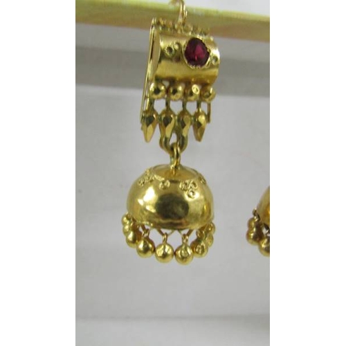 124 - A pair of (test as 24ct gold) pendant earrings set rubies.  10.4 grams.
