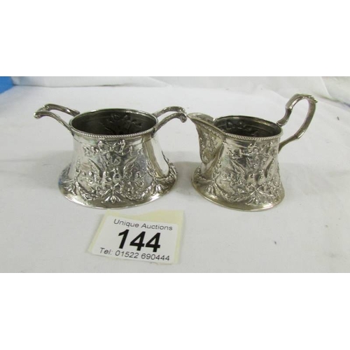 144 - A heavily embossed continental silver cream jug and sugar bowl, marked 800.