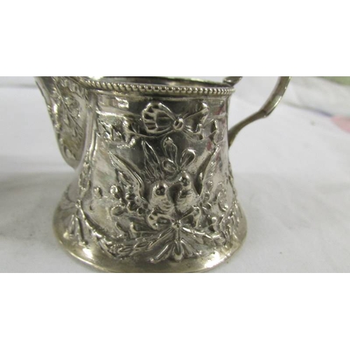 144 - A heavily embossed continental silver cream jug and sugar bowl, marked 800.