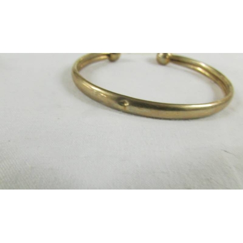 25 - A 9ct gold bangle, 9.5 grams.  (small dint).
