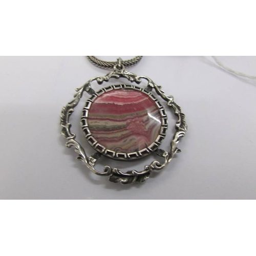 56 - A fancy silver open work pendant with attached silver chain and set with pink/grey banded agate, cir... 