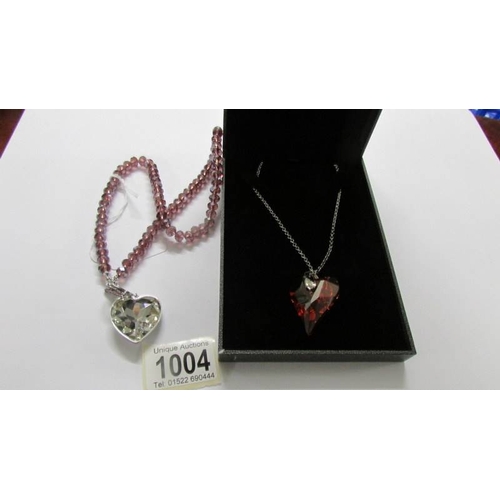 1004 - A Fiorelli heart pendant in silver and a heart pendant in shades of pink, lengths approximately 65 a... 