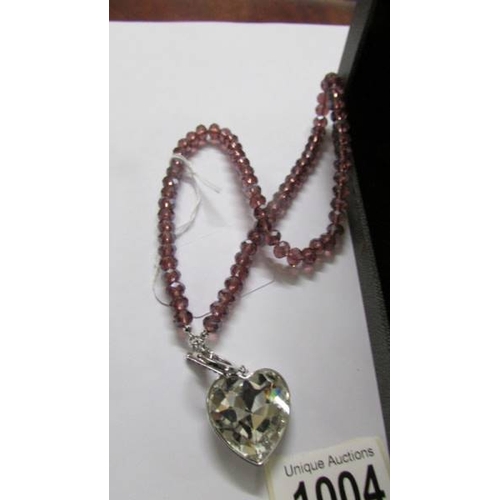 1004 - A Fiorelli heart pendant in silver and a heart pendant in shades of pink, lengths approximately 65 a... 