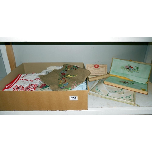 258 - A box of vintage textiles including embroidered household linens. mats & handkerchiefs