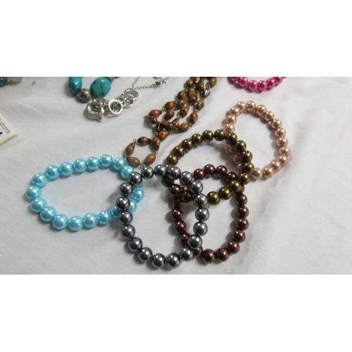 1041 - A black rope necklace, 5 other necklace and a quantity of coloured bracelets.