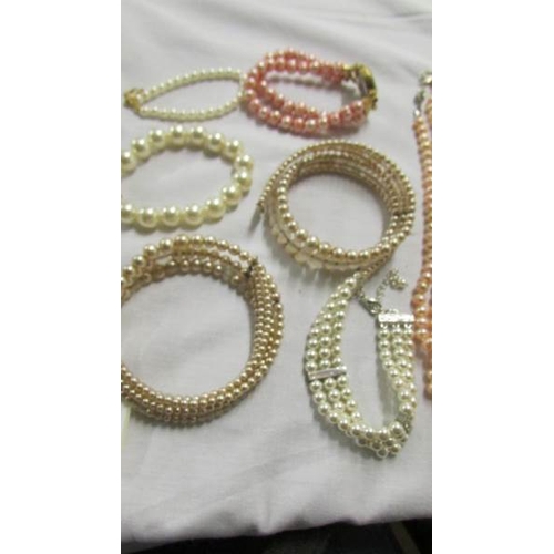 1055 - A quantity of 'pearl' necklaces and bracelets.