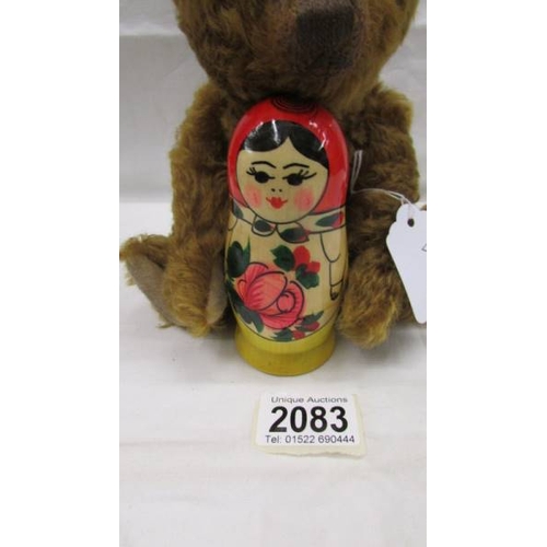 2083 - A small Steiff teddy bear holding a Russian doll in good condition.