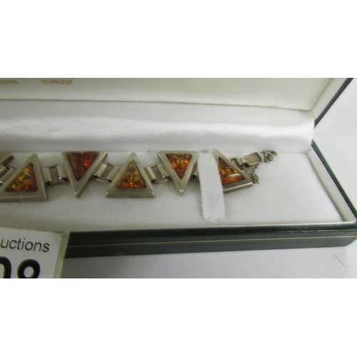 2108 - An amber bracelet set in silver designed a triangles in textured silver.