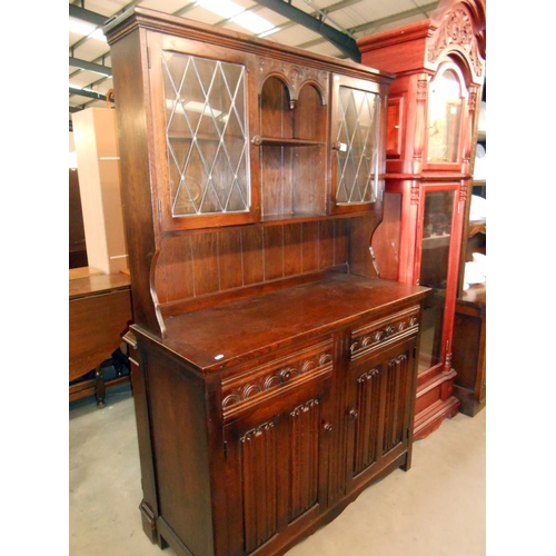 369 - A dark oak cottage dresser with leaded glass doors and drape carved panels, also has cutlery drawer ... 