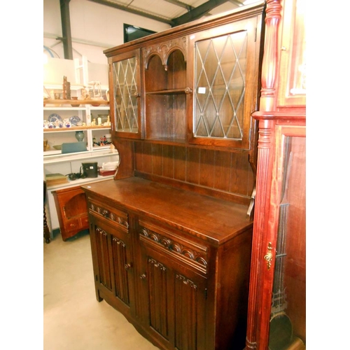 369 - A dark oak cottage dresser with leaded glass doors and drape carved panels, also has cutlery drawer ... 