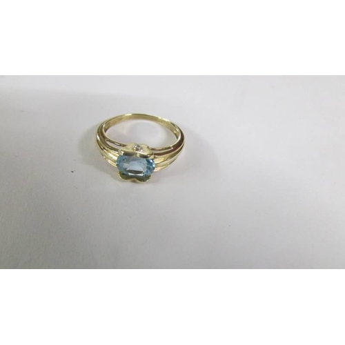 2124 - A blue topaz oval cut ring with 2 diamonds set in mount in 9ct gold, size P.