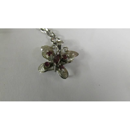 2128 - A garnet set butterfly in a silver mount on attached silver chain together with a sapphire set penda... 