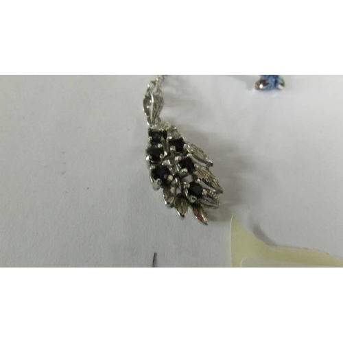 2128 - A garnet set butterfly in a silver mount on attached silver chain together with a sapphire set penda... 