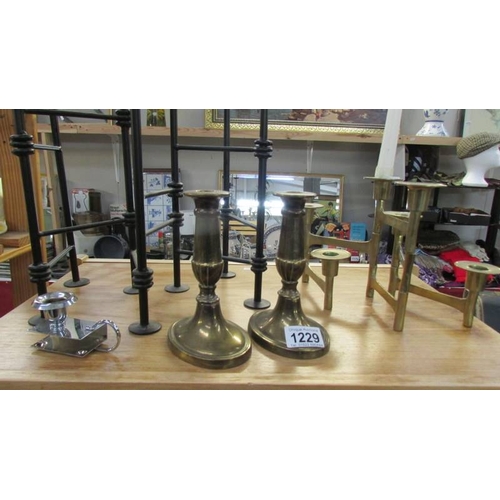 1229 - A wrought iron candleholder, a pair of brass candlesticks and other candlesticks.