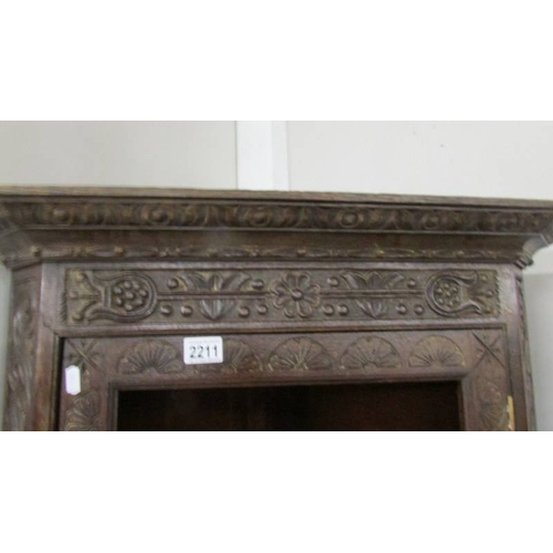 2211 - An antique carved oak corner cabinet (missing glass from door).