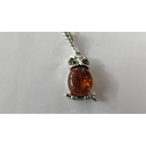 2264 - A silver owl pendant set with amber coloured stone on a white metal chain.