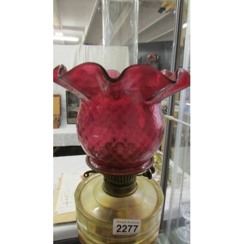 2277 - A Victorian oil lamp with brass column, glass font and complete with burner, shade and chimney.