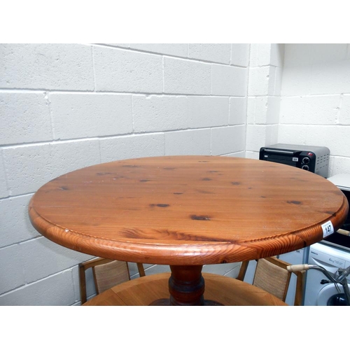 147 - A solid dark pine round kitchen table on centre column with 4 legs