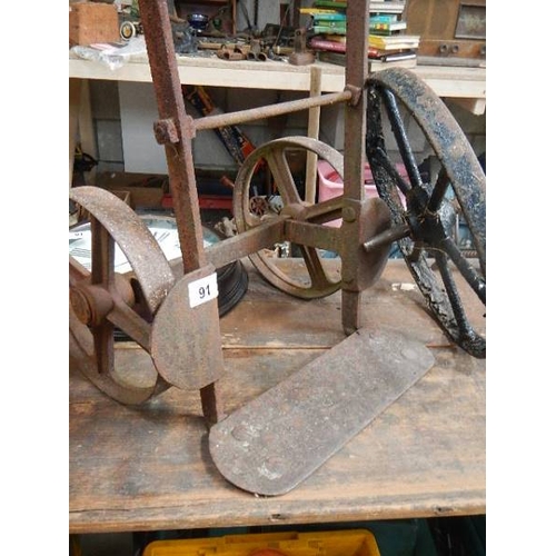 91 - An old metal trolley and a cast wheel.
