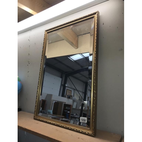 1058 - A gilt framed bevel edged mirror. (Collect only)