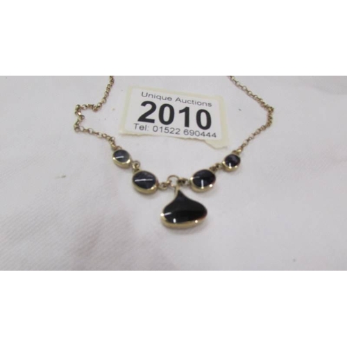 2010 - A pretty 9ct gold necklace set dark coloured stones. 7.6 grams.