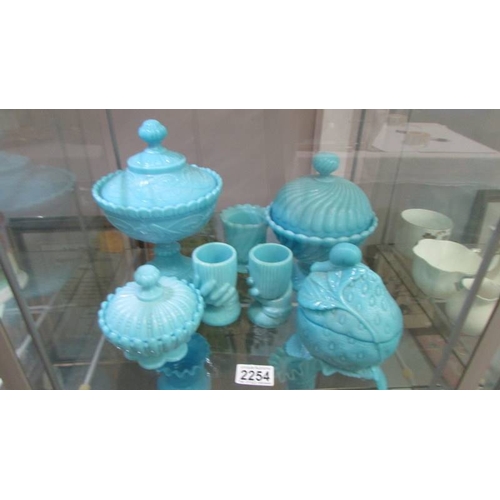 2254 - A mixed lot of blue glass including lidded bowls, vases, pots etc., 15 items in total (2 shelves). (... 