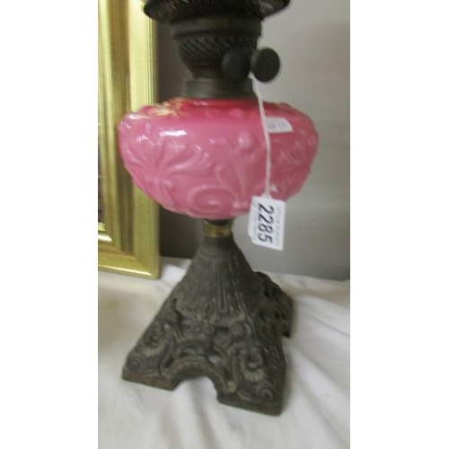 2285 - A 19th century oil lamp with pink glass font on a cast iron base and with original acid etched shade... 