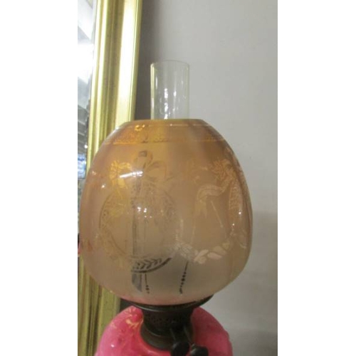 2285 - A 19th century oil lamp with pink glass font on a cast iron base and with original acid etched shade... 